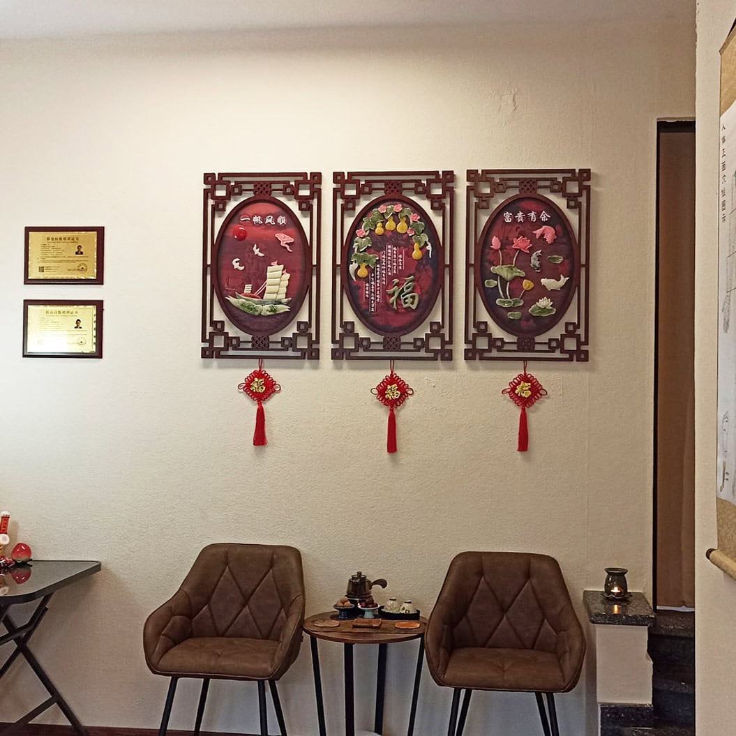 Zwei braune Sessel vor einer Wand mit chinesischen Kunstwerken und Zertifikaten, traditionell eingerichtet.